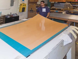 Veneer faces are laminated to aluminum cores, sanded, and finished. This photo shows panels after application of an ultraviolet (UV)-cured coating free of volatile organic compound (VOC) emissions. The flexible sheets are made rigid and flat when edge returns are formed.