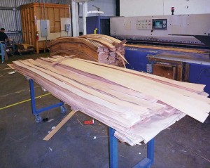 Veneer is trimmed and short lengths glued end-to-end to make strips. Strips are then joined edge-to-edge in order to make faces large enough for required panels.