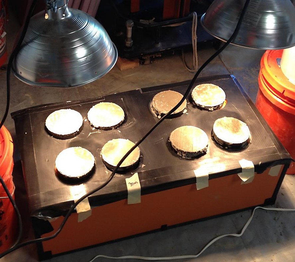 This heating curing box and the heat lamps overhead were used simulate field conditions similar to an outdoor pour in the Southwestern United States. The samples cured in this setup were tested for permeability using the rapid chloride ion permeability test. Photo courtesy Intelligent Concrete laboratories