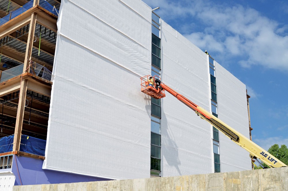 A building wrap air and water barrier system is installed over the exterior sheathing, prior to the installation of metal panels. Proper installation is critical for meeting the building envelope structural wind loads and maintaining the air barrier continuity over time.