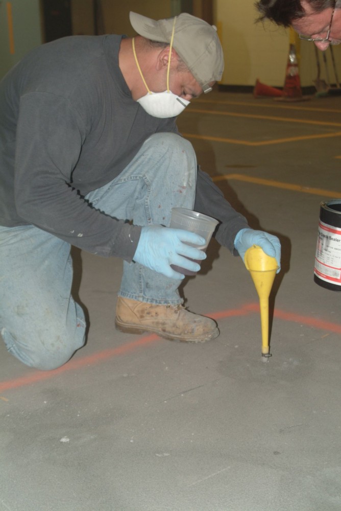 Gravity-feeding an epoxy healer/sealer can repair cracks on a concrete deck.