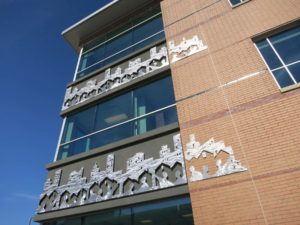 Original artwork on the building’s façade depicts abstract human figures holding hands in the foreground with houses and urban cityscapes behind them, symbolizing Continuum’s core values of ‘home’ and ‘community.’ Photo courtesy Svigals + Partners