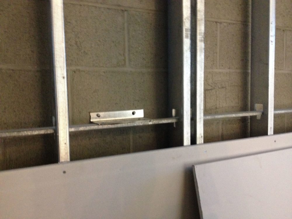 Lateral support bridging a structurally separated stud wall