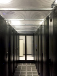 Translucent drop-out panels are installed between racks of computer servers as part of cold-aisle containment systems. Filtered and refrigerated air is blown through the plenum to cool the electronic devices. Locating fire sprinklers and light fixtures outside the conditioned zone prevented air loss through ceiling penetrations and heat gain from lamps. It also preserves headroom, simplifies housekeeping, and allows technicians working inside aisles and on top of racks to have visual contact. Photo courtesy Instor Solutions Inc.