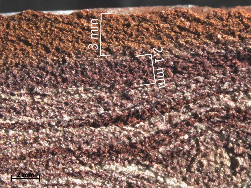 Photomicrograph of sawn section of brick showing distinctive layers of different materials and angular sand particles included in the brick as filler.