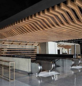 A custom-designed shelf wall fits above the escalators to define a main entrance to the facility and extend the wood ceiling aesthetic.