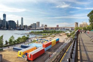 Spacesmith with partner firm Davis Brody Bond transformed a riverside stretch into a pop-up pool in Brooklyn, New York. Shipping containers painted in bold, primary colors were repurposed as storage space. They also act as a buffer to the noise of a nearby expressway.