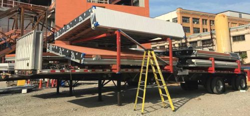 Panels arrive onsite on a flat-bed truck, waiting to be lifted into place.