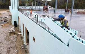 Installer stacks insulated concrete forms (ICFs) blocks on the second story of this school building.