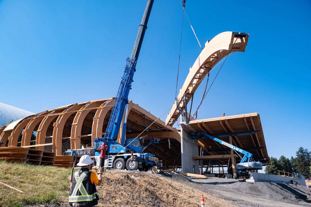 The photo shows the installation of the final truss on the roof.