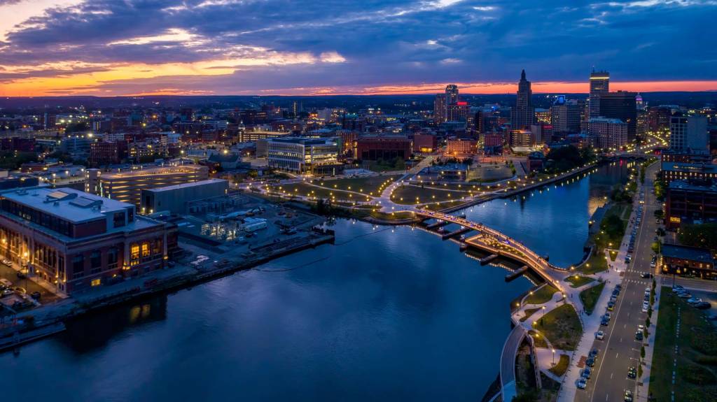 A long shot aerial view of the bridge, lit up at night within the cityscape.