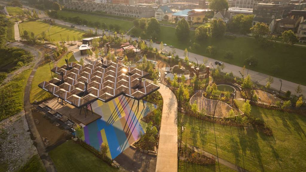 The brightly painted basketball court, a piece of public art conceptualized by a Memphis artist, lies next to a wooden public deck under the canopy.