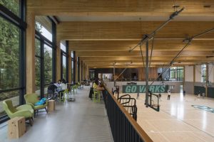 The basketball court flanked by the seating areas facing the glass and mass timber wall at the facility’s front facade.