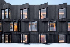 The accommodation area spans three floors. The facade is composed of metal, timber siding, and glass, with glimpses of exposed mass timber inside.