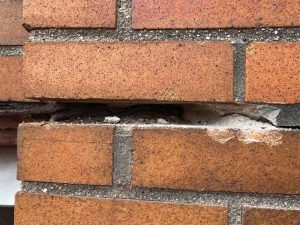 Deteriorated and open mortar joint in a brick masonry wall resulting from jacking of the adjacent corroded steel window lintel and freeze/thaw damage.