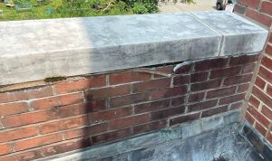 Deteriorated sealant resulting from adhesion failure and inappropriate placement of sealant at a coping bed joint, where water became trapped in the adjacent mortar and caused freeze/thaw damage and biological growth.