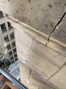 Vertical cracking in historic stone masonry wall assembly resulting from a lack of movement joints to allow for differential settlement and thermal expansion.