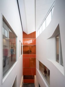 Atrium stretches in front of an area of administrative offices, hidden behind orange galss.