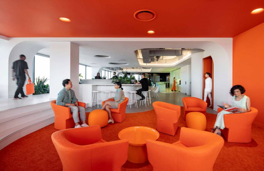 An orange meeting area with a white area in the background, punctuated by a light green lunchroom.