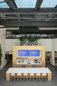 The open-layout kitchen and lunch area carries seating by a long table for employees to sit and eat and watch TV.