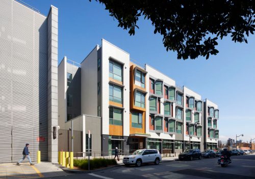 Housing apartment with cars parked in front of it.