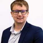 man in a suit and spectacles smiling at the camera