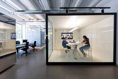 two people working in a glass-covered cube office