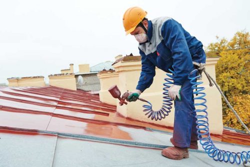 roofer working on top a building with construction hate and paint