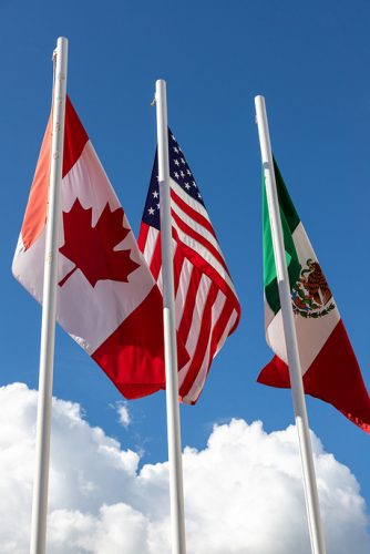 Flags of United States, Mexico, Canada flying together, concept of new NAFTA agreement now known as USMCA in the U.S., CUSMA in Canada or T-MEC in Mexico.