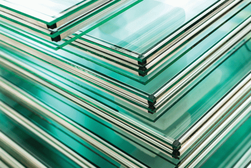 Close-up of stacked glass panels with protective sealant applied along the edges, highlighting the finishing process in glass manufacturing.