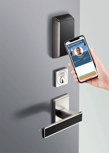 A person is using a smartphone to interact with a smart door lock on a gray door. The phone displays a user profile from a university app, while the lock features a traditional keyhole and a digital access point above it.