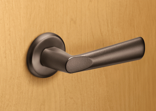 A dark metal door handle is mounted on a smooth, light-colored wooden door. The handle has a sleek, modern design with a rounded base and an elongated grip.