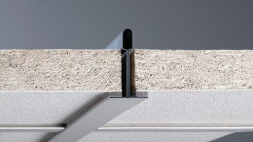 A close-up view of a metal channel positioned on top of a textured board. The channel appears sleek and is partially embedded within the board, highlighting the connection between these two materials. The background is neutral, focusing on the materials.