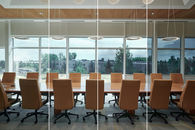 Conference room with a long table and orange chairs, featuring large windows and a view outside.