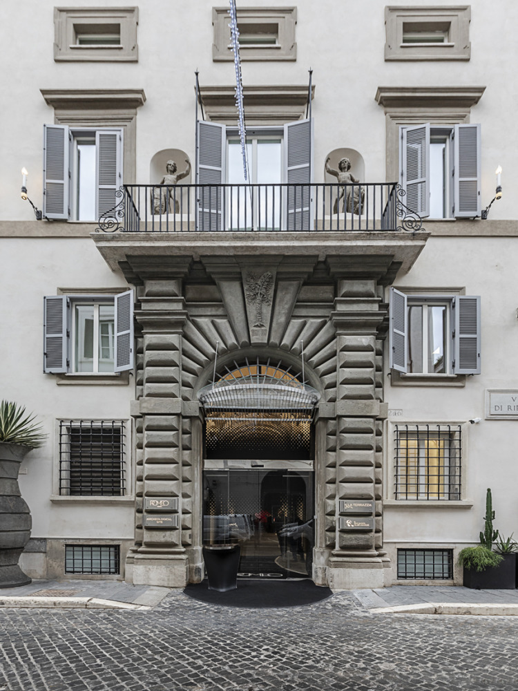 Romeo Roma Hotel entrance with ornate stonework, arched doorway, and classic shuttered windows